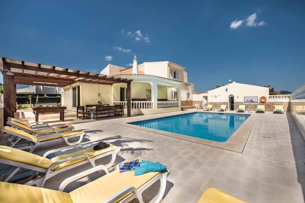 a villa with a swimming pool and lounge chairs at Carvoeiro Villa Miguel in Carvoeiro