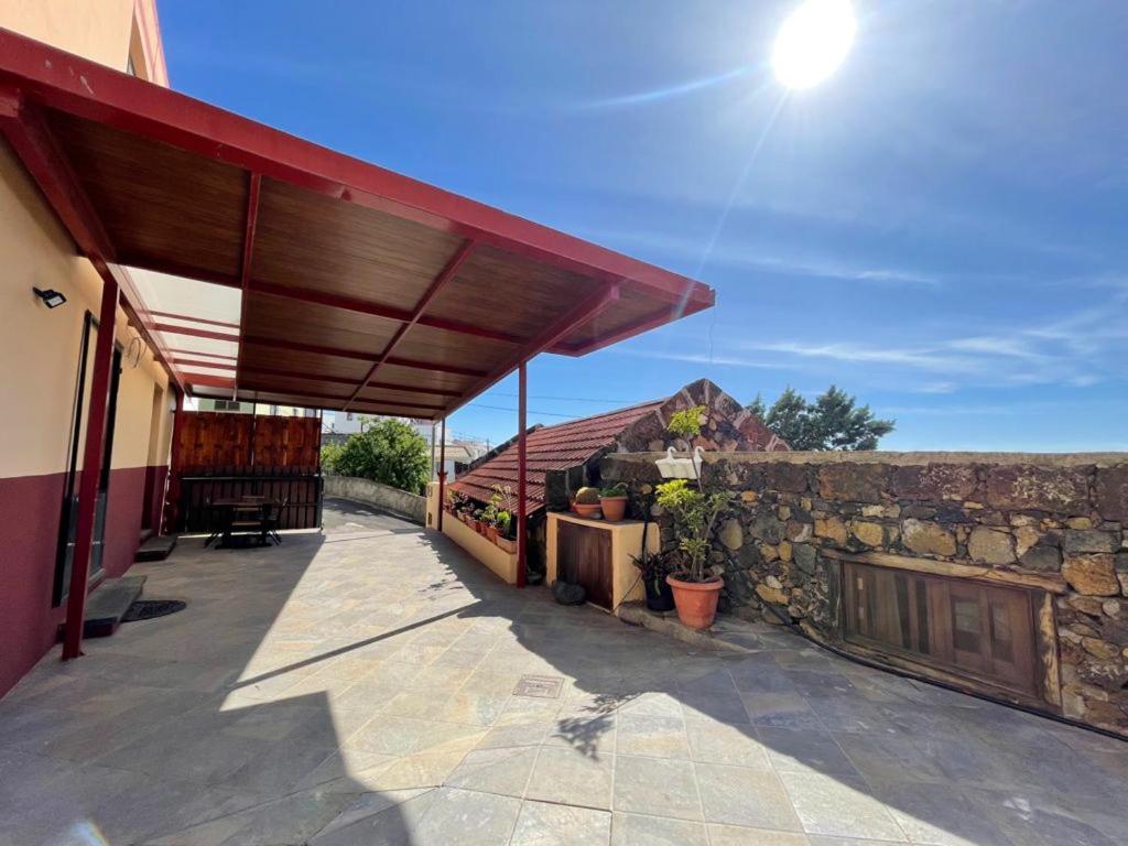 um pátio com um telhado vermelho e uma parede de pedra em 2 bedrooms house with sea view furnished garden and wifi at Taibique em Taibique