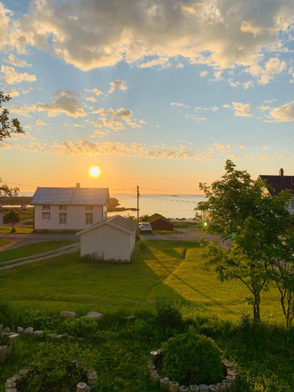 a house in a field with the sunset in the background at Drømmefabrikken in Bleik