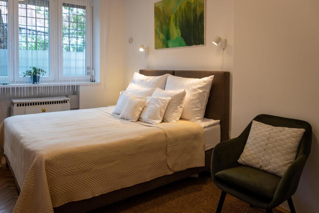 Cette chambre comprend un lit avec des oreillers blancs et une chaise. dans l'établissement Sunbird Apartman Budapest, à Budapest
