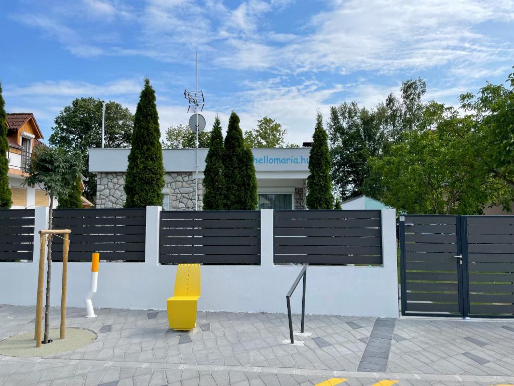 una valla blanca con bancos frente a un edificio en HelloMária en Balatonmáriafürdő