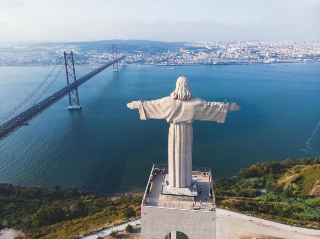 a statue of christ the redeemer in front of a bridge at Almada Cristo Rei in Almada