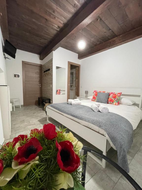 a bedroom with a bed with red flowers in the foreground at B&b Le Larie in Collepardo