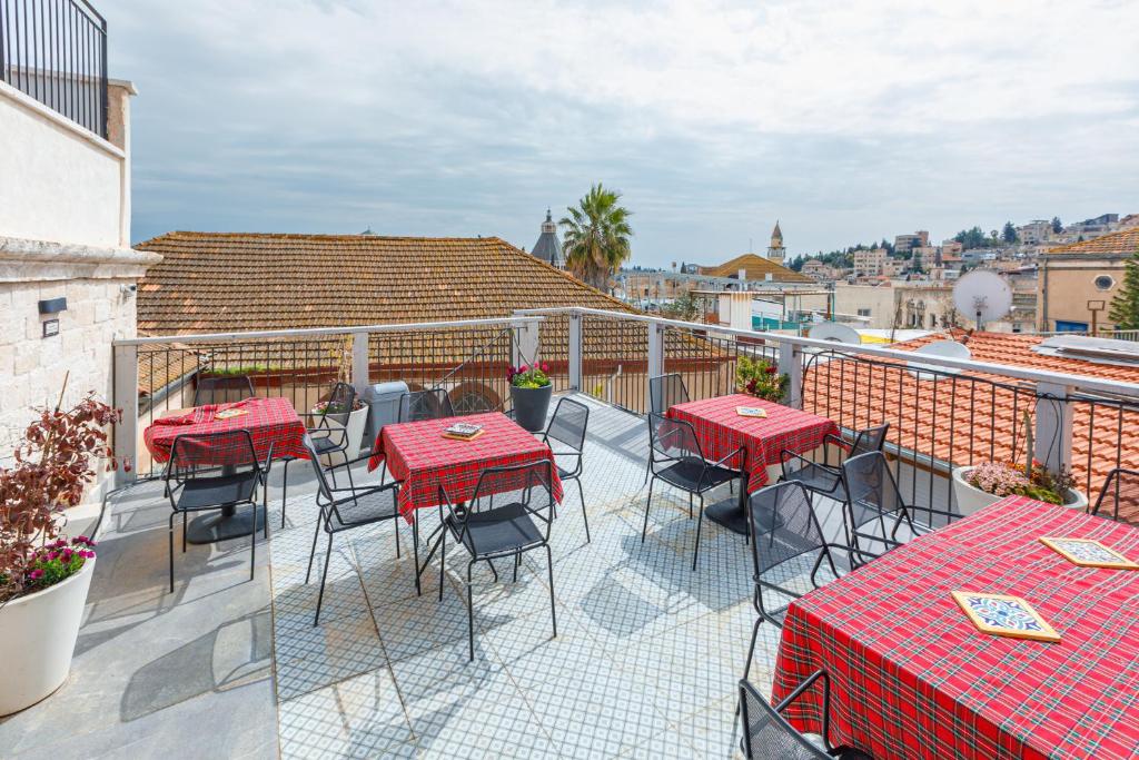 a patio with red tables and chairs on a balcony at Michel House in Nazareth