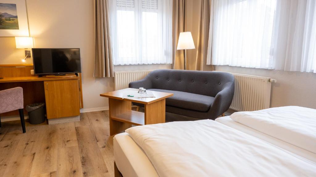 Habitación de hotel con cama, silla y TV en Pension Sellent, en Stendal