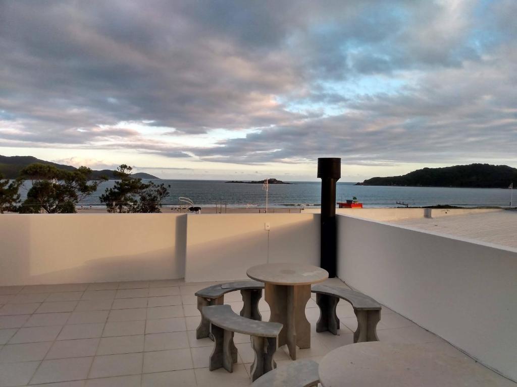 uma mesa e duas cadeiras numa varanda com praia em Apartamento Ilha do Coral em Palhoça