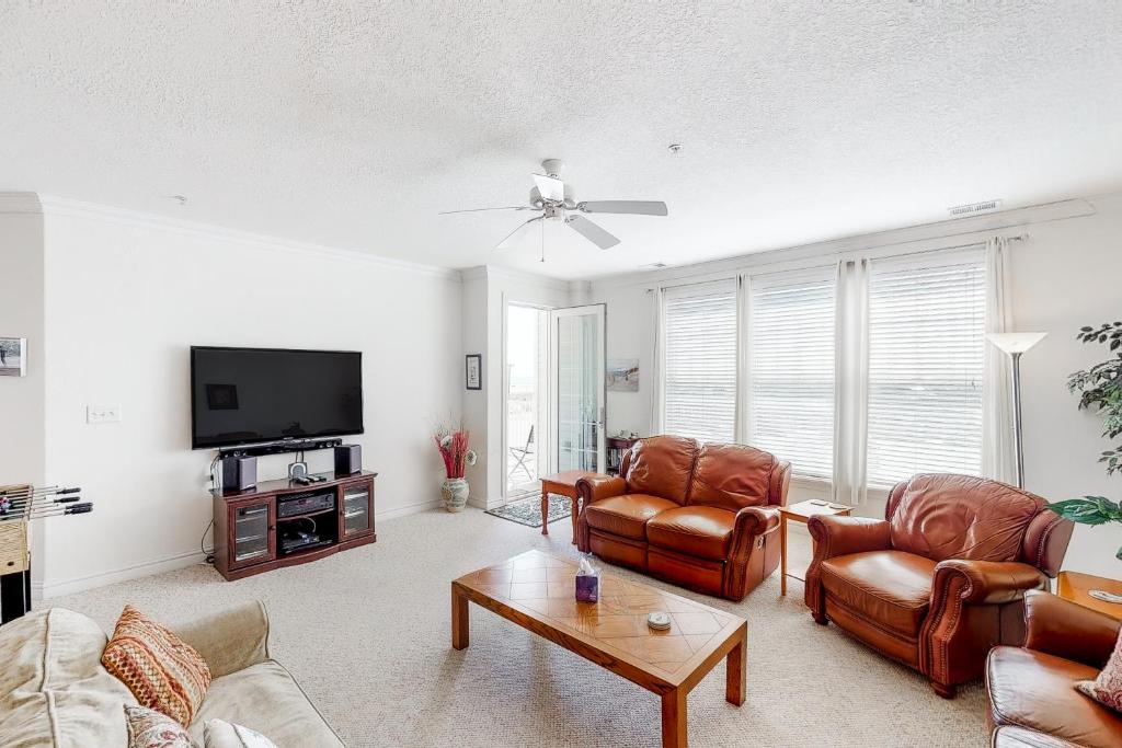 sala de estar con muebles de cuero y TV de pantalla plana en The Sandbridge Dunes - Serenity 206, en Virginia Beach