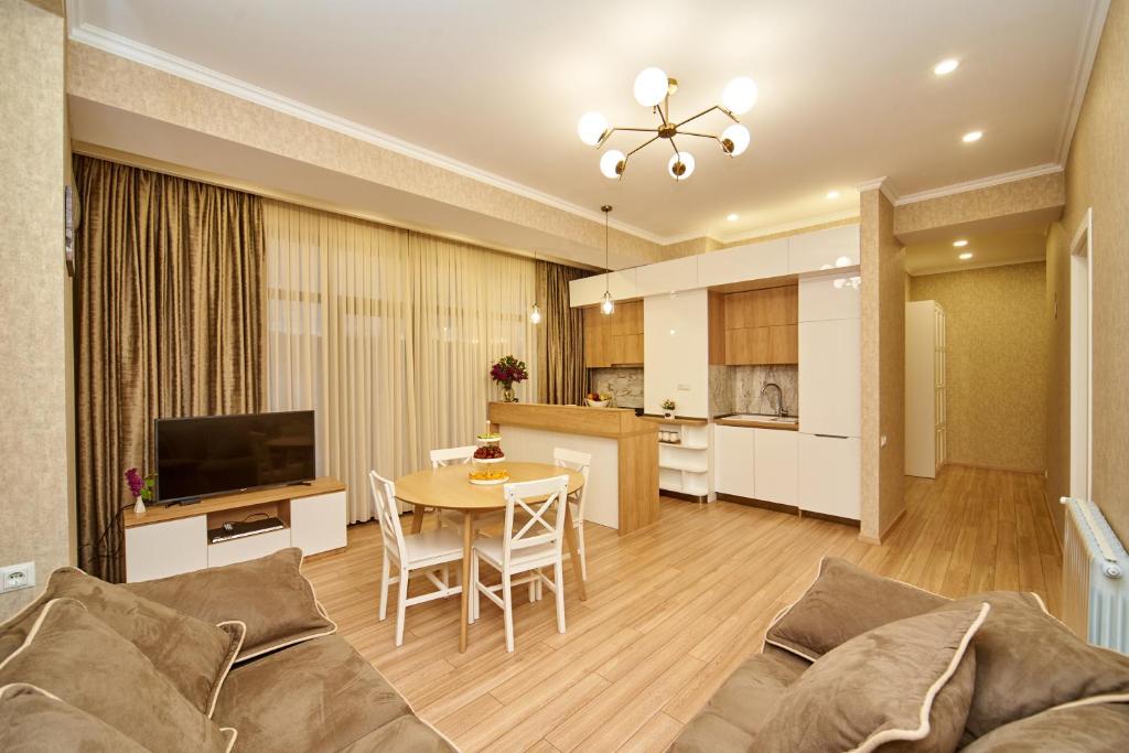 Apartment by the river في تبليسي: غرفة معيشة مع أريكة وطاولة ومطبخ