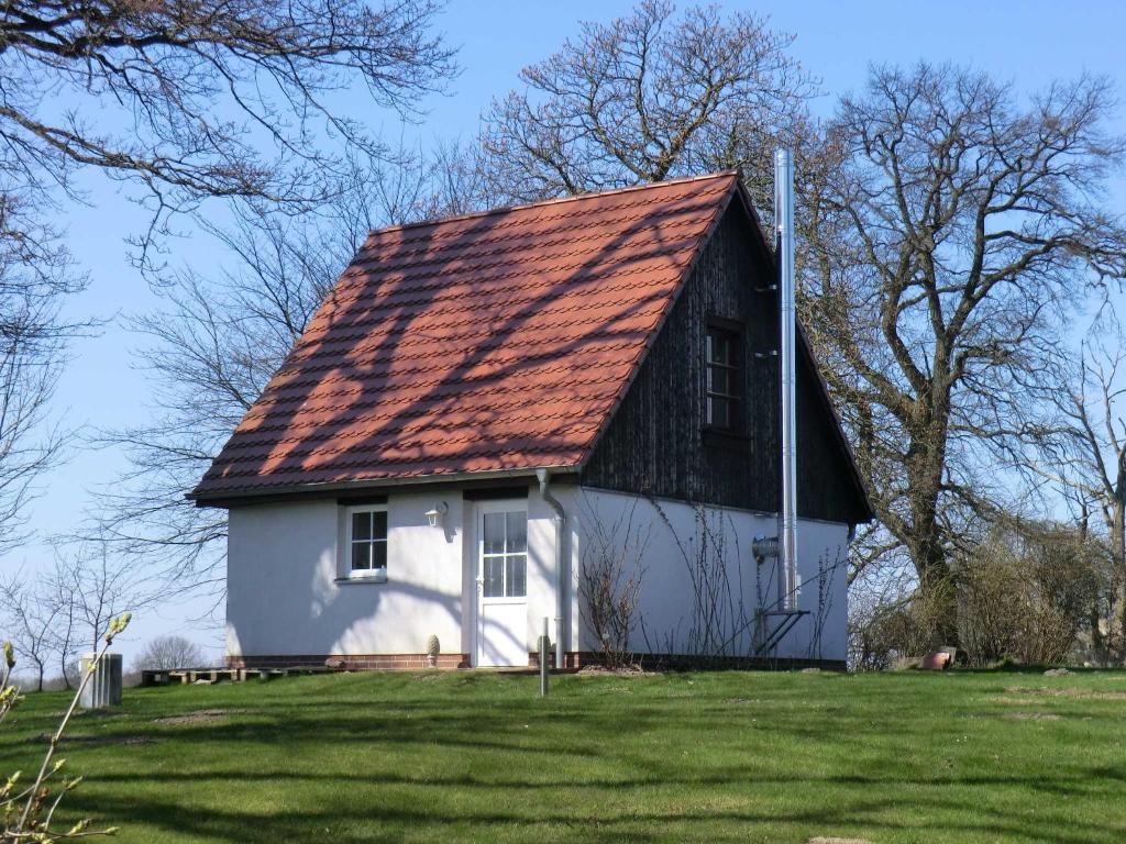 a white house with a red roof on a green field at FerienGut Dalwitz Kitzklause in Walkendorf