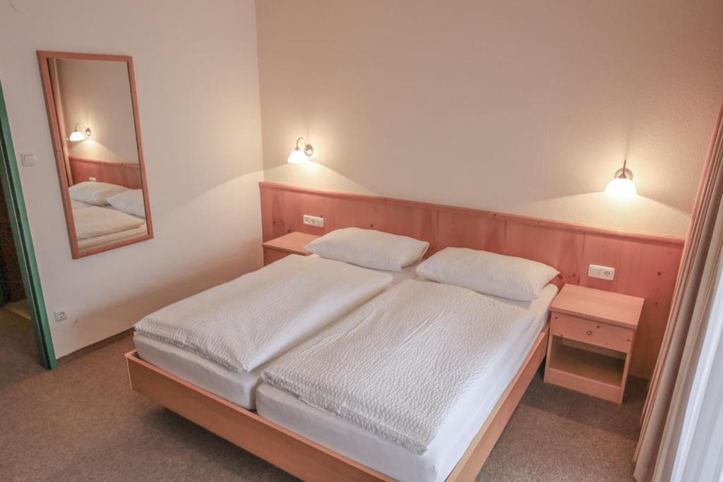 a bedroom with a bed with two pillows and a mirror at Gasthof Pension Pichlernwirt in Himmelberg