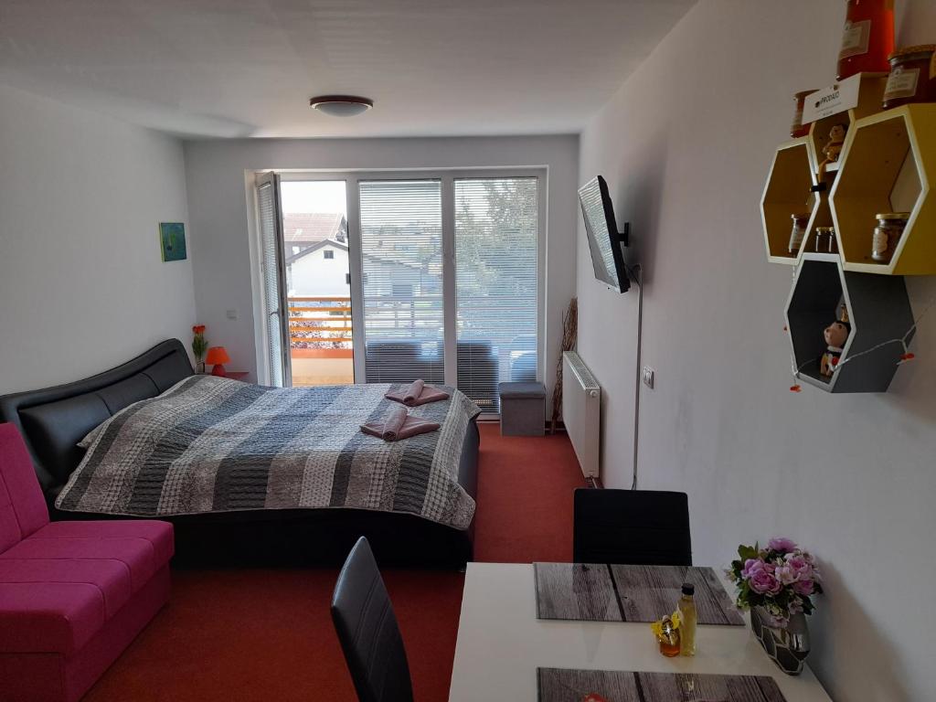 a bedroom with a bed and a pink couch at Honey Apartment in Moravske Toplice