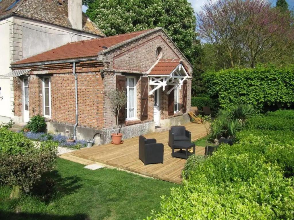 a house with a wooden deck in the yard at Le Pavillon de la mare in Avrainville