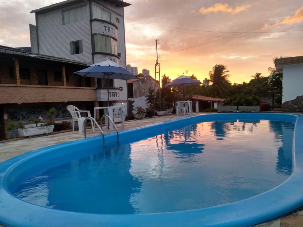 una gran piscina con puesta de sol en el fondo en Pousada Toca do Tato, en Natal