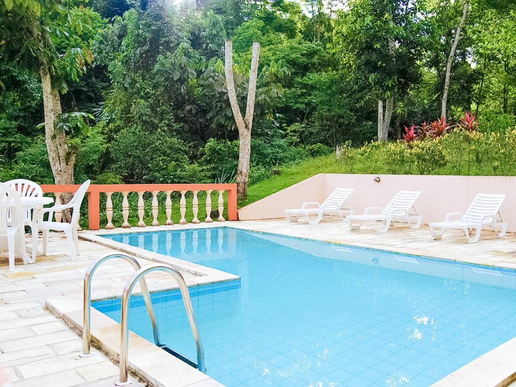 uma piscina com cadeiras e uma mesa e uma mesa e cadeiras em Pousada Canto do Curió Paraty em Paraty