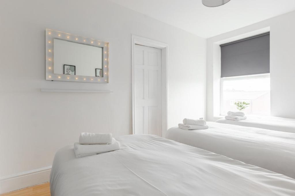 een witte slaapkamer met een bed en een spiegel bij RST Stanley Park in Liverpool
