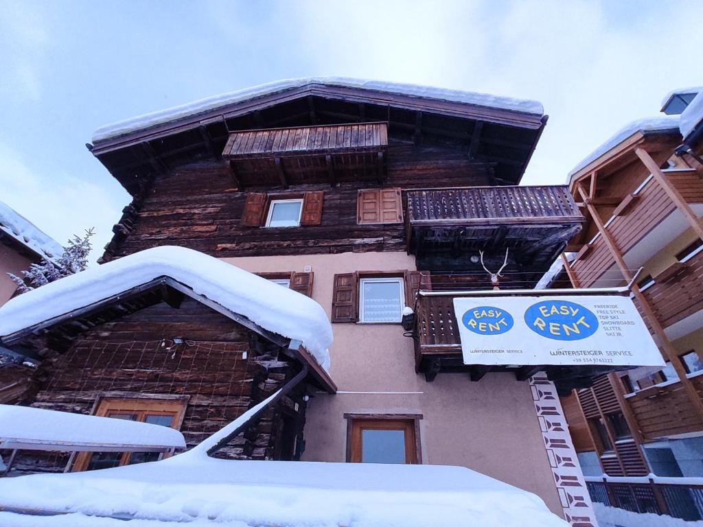 un edificio cubierto de nieve con un cartel. en Loft Mountain Spirit en Livigno