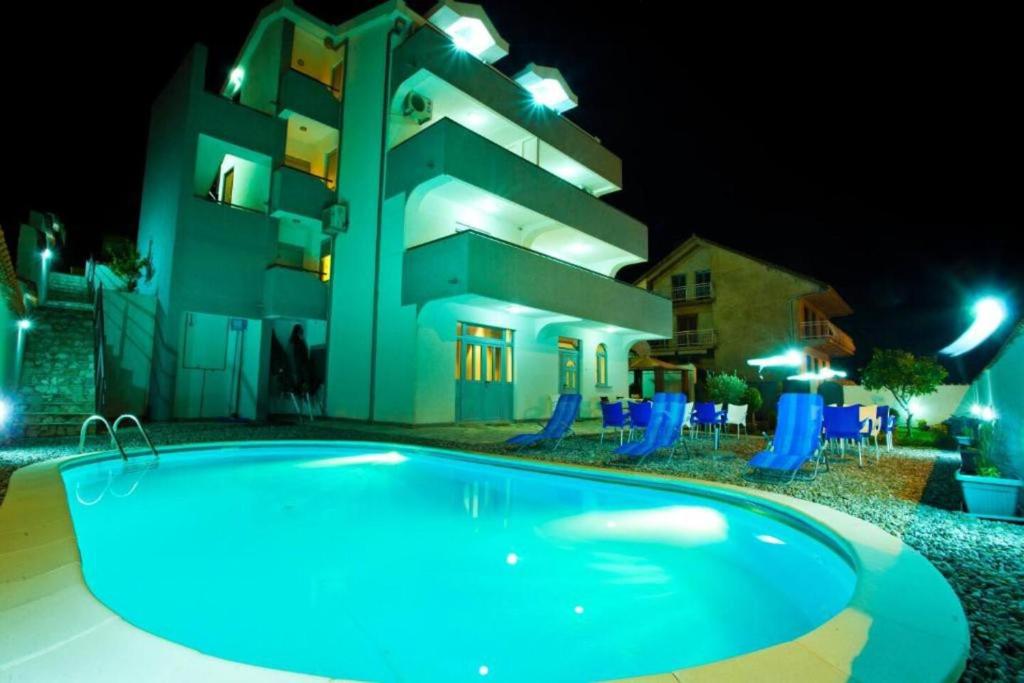 a swimming pool in front of a building at night at Gemma di Cattaro Apartments in Kotor
