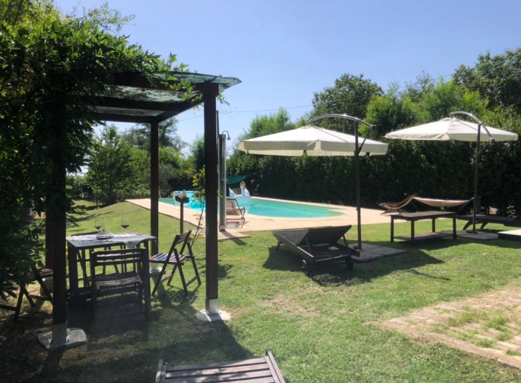 a backyard with a pool with tables and umbrellas at Lodge, in mezzo alla natura in Roccatederighi