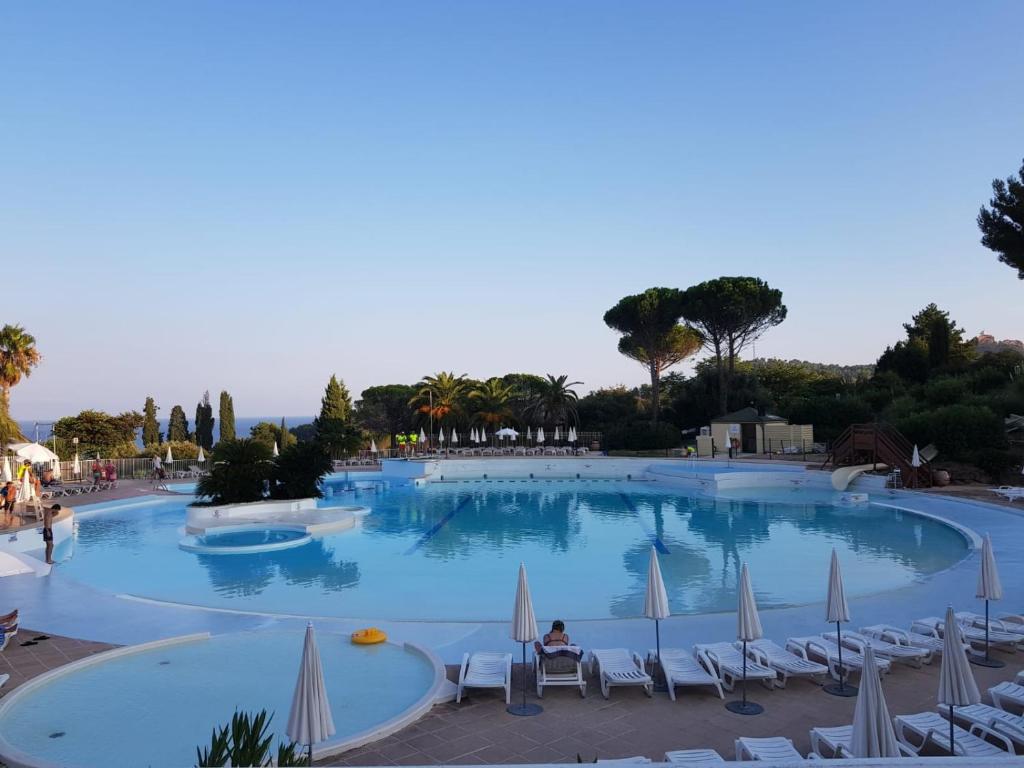 a large swimming pool with chairs and umbrellas at Cap Esterel face à la mer Agay St Raphael in Drammont