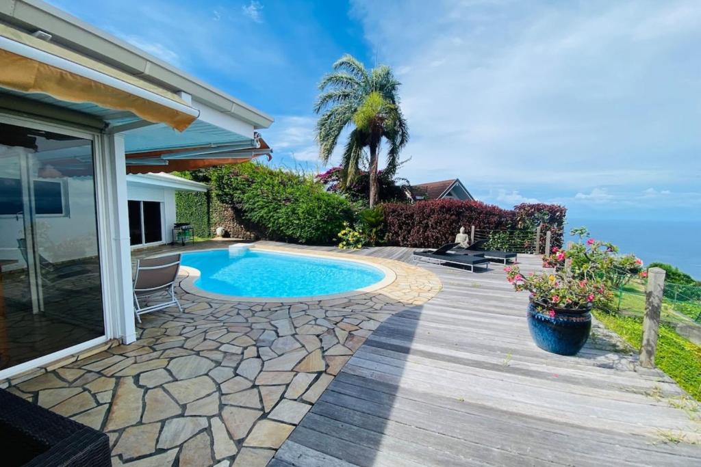 un patio trasero con piscina y terraza de madera en VILLA BOUNTY AMAZING OCEAN VIEW en Punaauia