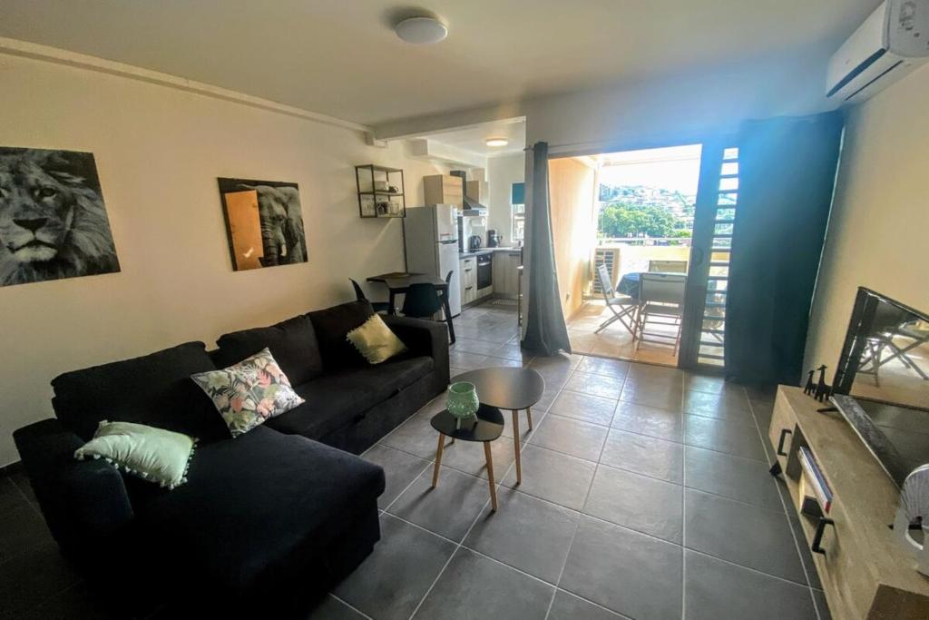 a living room with a black couch and a table at Recent Bel Appartement une chambre Papeete in Papeete