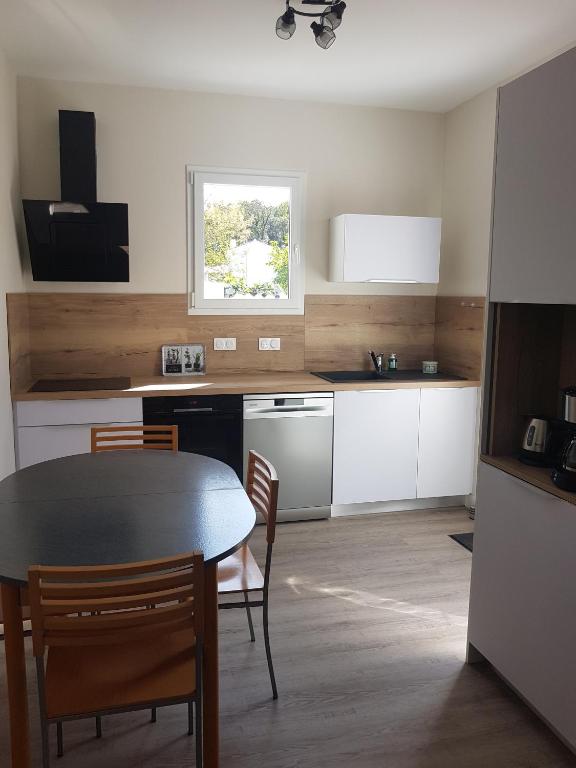 - une cuisine avec une table, une table et des chaises dans l'établissement EOLE - Maison Saint Jean de Monts - 2 pièces - 4 personnes, à Saint-Jean-de-Monts