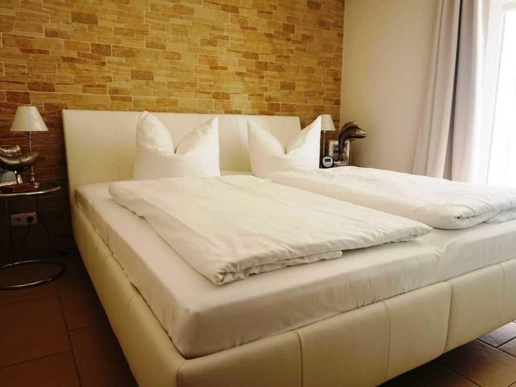 a large white bed with white sheets and pillows at Dünendomizil strandnah in Bansin