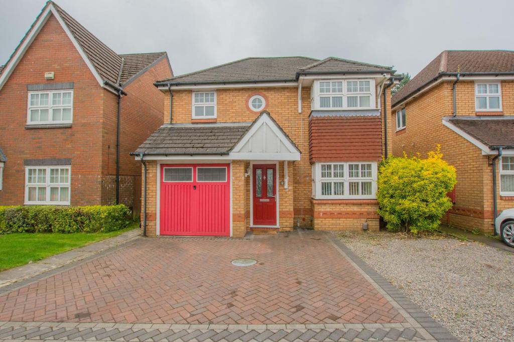 a brick house with a red door and a driveway at Modern 4 Bedroom Detached House in Cardiff in Cardiff