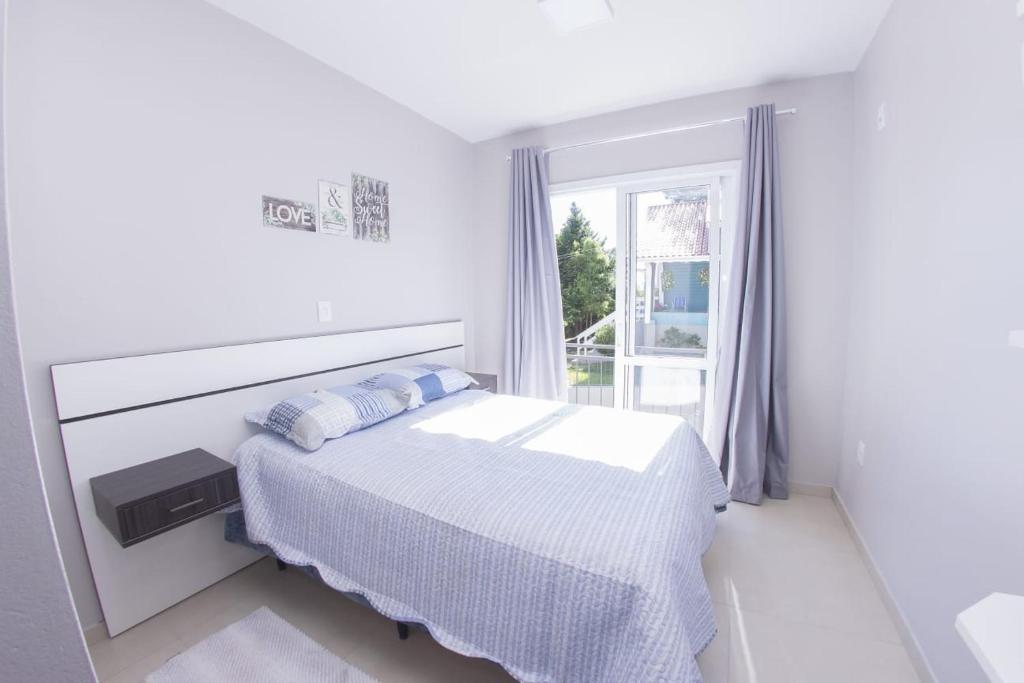 - une chambre blanche avec un lit et une fenêtre dans l'établissement Residencial Vó Nilda II, à Canela