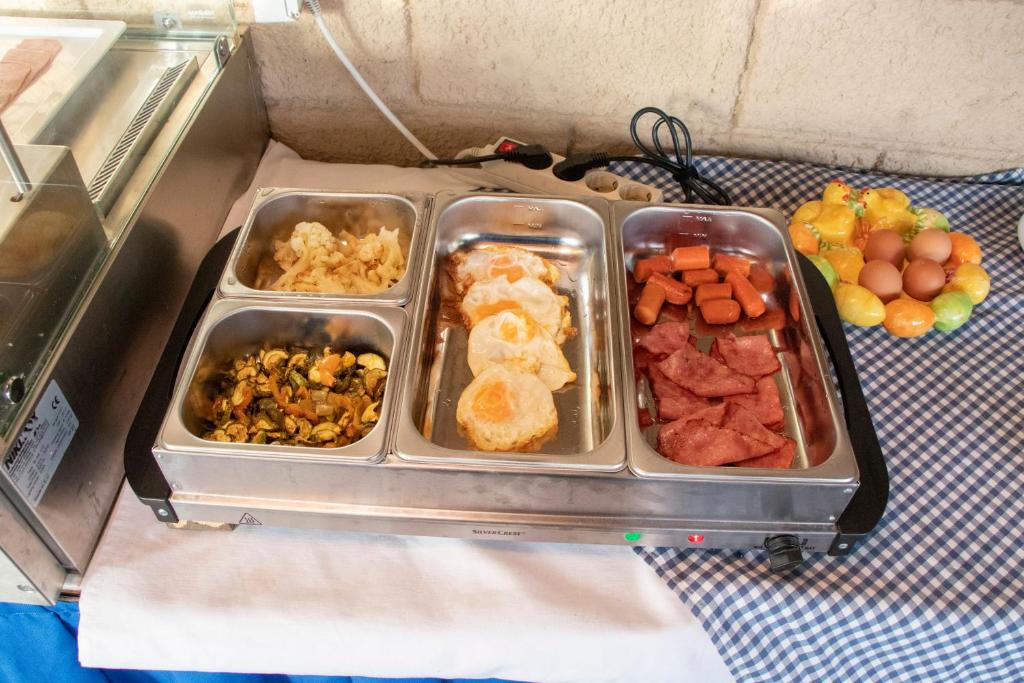 a lunch box with four trays of food on a table at Villa Bel Passo Apartments in Kefalos