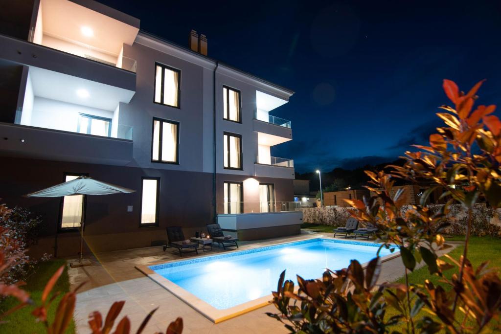 a villa with a swimming pool at night at Luxury apartment Punta with sea view and swimming pool in Premantura