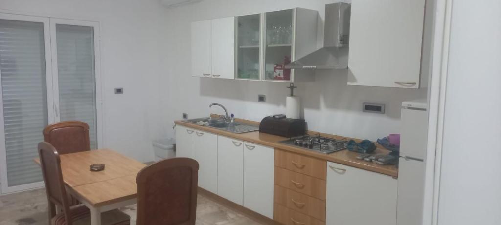 uma cozinha com armários brancos e uma mesa de madeira em CHIARANTO em Menfi