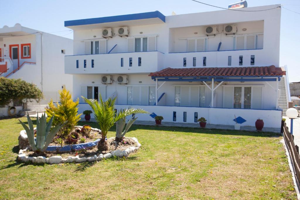 un edificio blanco con palmeras delante en Villa Bel Passo Apartments en Kefalos
