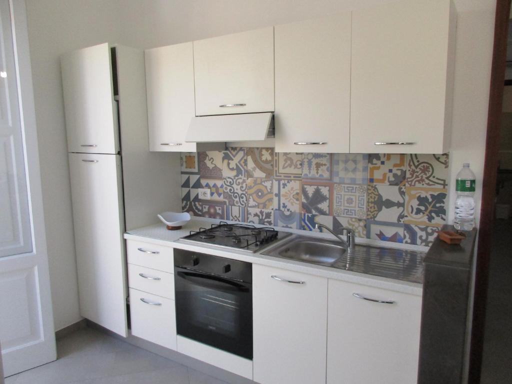 a kitchen with white cabinets and a stove and a refrigerator at Le Case Di Tufo- Casa del sole in Favignana