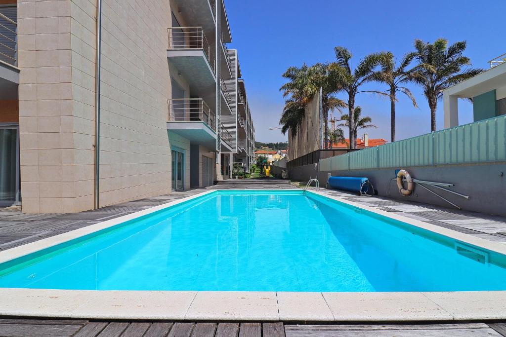 a swimming pool in the courtyard of a building with palm trees at Baía Residence I - Beach and Rest in São Martinho do Porto