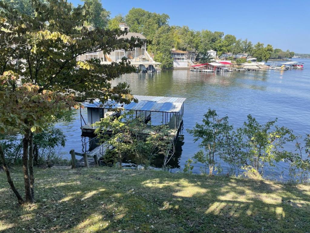 una casa en un muelle sobre un cuerpo de agua en Cozy Lake Cabin Dock boat slip and lily pad, en Lake Ozark