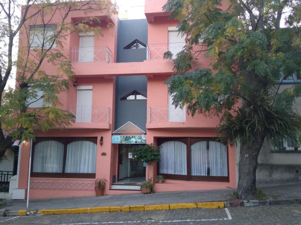 een roze gebouw met een boom ervoor bij Hotel Perla del Plata in Colonia del Sacramento