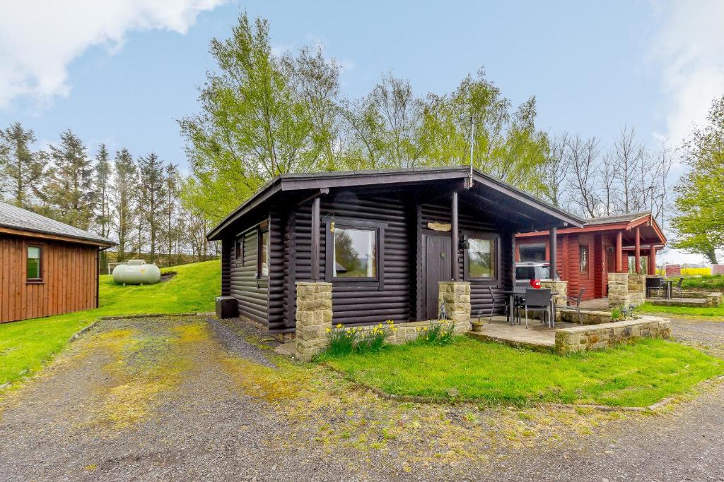 a log cabin with a porch and a house at Harbottle Lodge in Longframlington