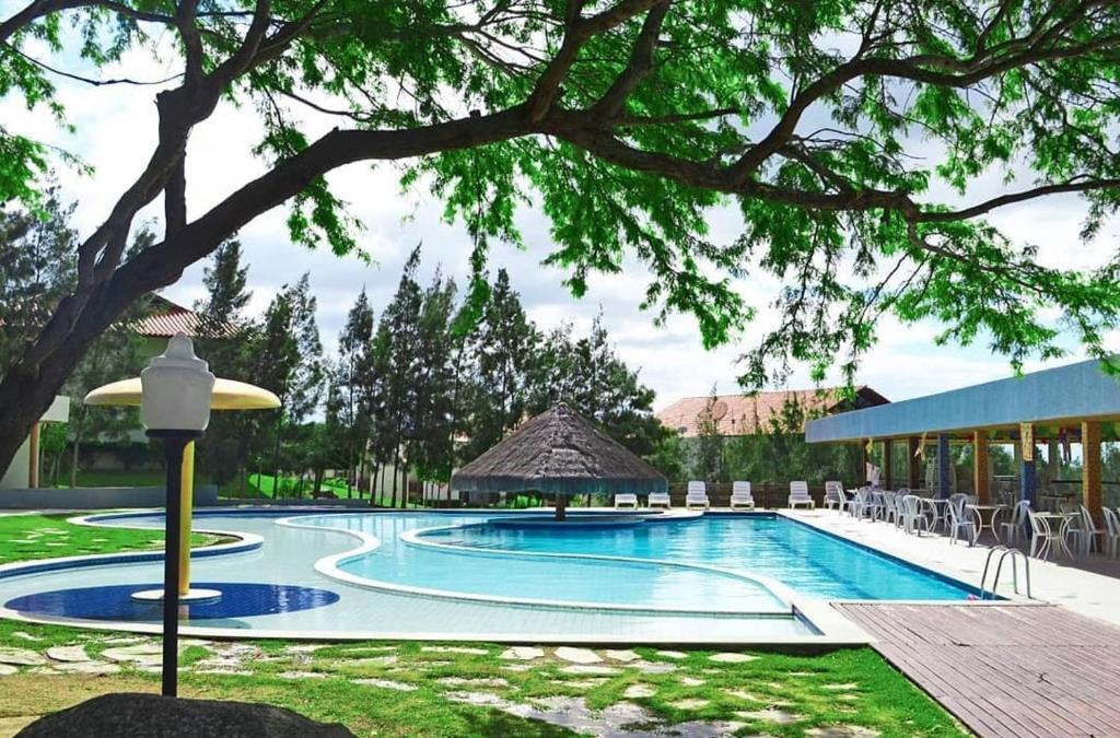 a large swimming pool with chairs and a building at Monte Castelo Gravatá - Flat Aconchegante in Gravatá