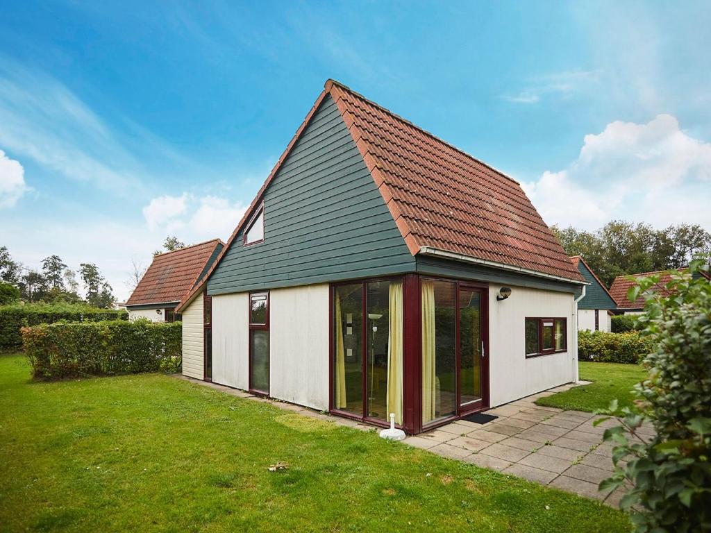 uma pequena casa branca com um telhado preto em Cozy holiday home with wellness located in Zeeland em heinkenszand