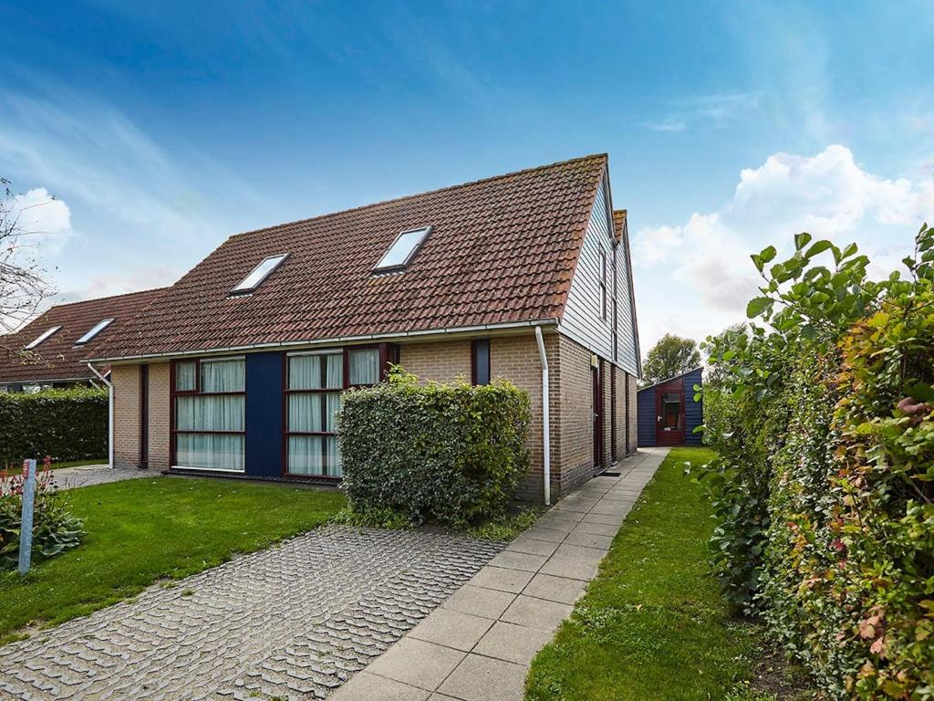 uma casa de tijolos com telhado castanho em Coy holiday home with large garden, in Zeeland em heinkenszand