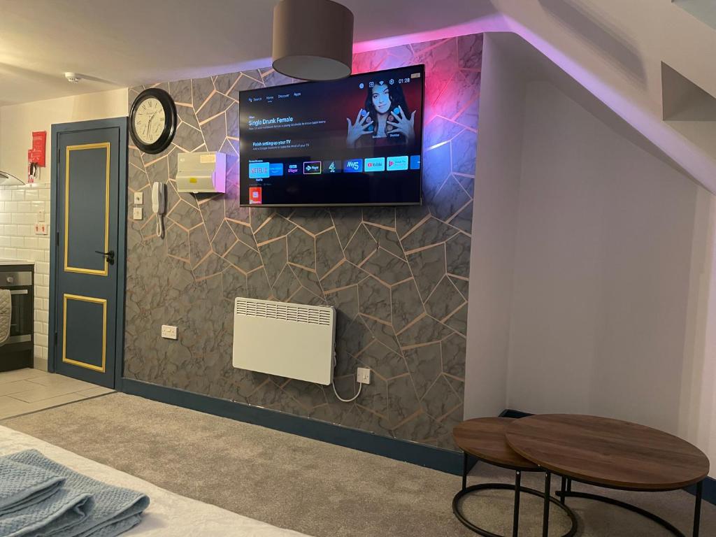 a room with a tv on a wall with a stool at Lovely studio apartment located in Birmingham in Birmingham