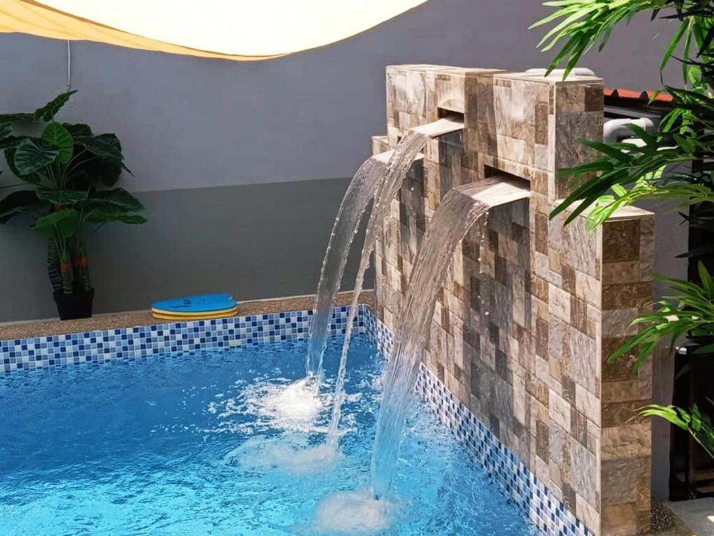 a water feature in a pool with a waterfall at Private pool Cassa Dinies, Wifi , Bbq,10 pax in Rantau Panjang