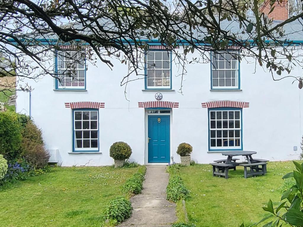 una casa bianca con una porta blu e un tavolo da picnic di Langford Barton a Bude