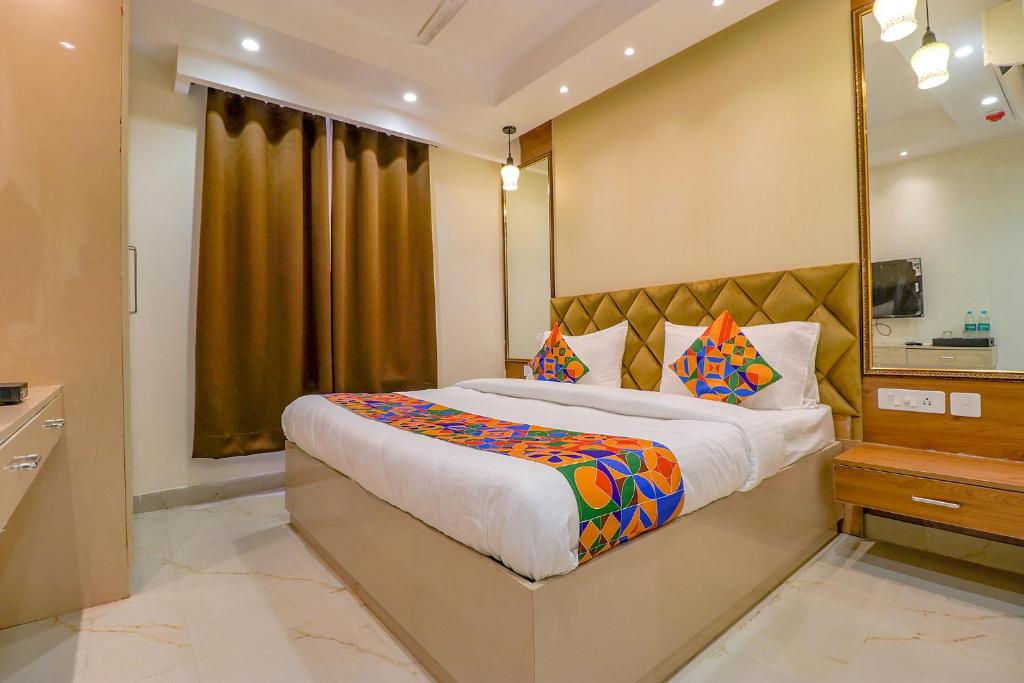 a bedroom with a large bed and a mirror at FabHotel F9 Pitampura in New Delhi