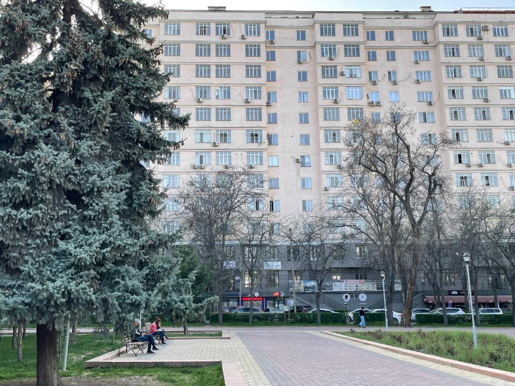 a large building with people sitting on benches in a park at Lovely house in the city center in Bishkek