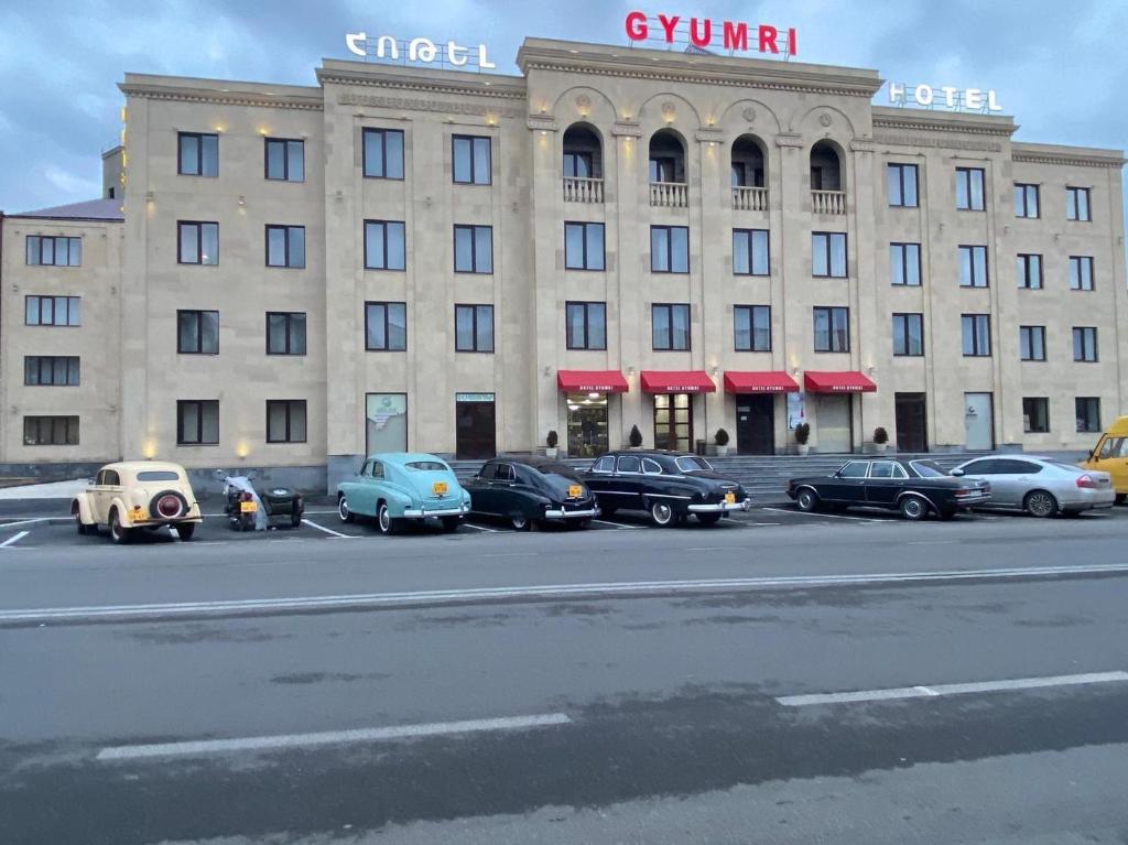 duży budynek z samochodami zaparkowanymi przed nim w obiekcie Gyumri Hotel w mieście Giumri