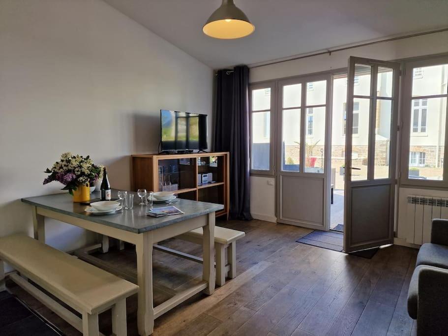 a living room with a table and a television at Le Château de Sable in Plougasnou