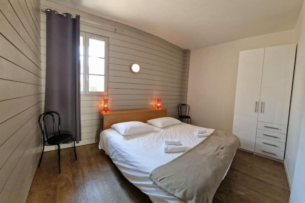 a bedroom with a large white bed with a window at Le Château de Sable in Plougasnou