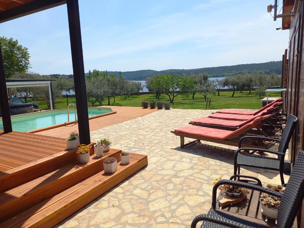 a patio with a bench and a swimming pool at Beach house BETA with pool, jacuzzi, playground & bbq in an olive grove with a beach, Pomer - Istria in Pula